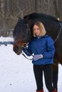 Portrait of a young girl with white hair next to a brown horse. The girl holds the horse and smiles. Close-up Royalty Free Stock Photo