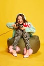 Portrait of young girl, woman in chic clothes holding popcorn and playing video games with tense face over blue studio Royalty Free Stock Photo