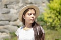 Portrait of a young girl of 17-20 years old in a white dress and a straw hat with long black hair against a stone wall and greener Royalty Free Stock Photo