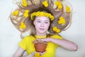 Portrait of a young girl with a yellow wreath of dandelions in her loose hair and a pot of honey in her hands. View from above