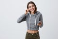 Portrait of young good-looking brunette caucasian student girl in casual gray hoodie and jeans smiling with teeth Royalty Free Stock Photo