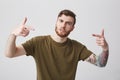 Portrait of young good-looking negative aggressive bearded tattooed male with short hair in casual stylish brown t-shirt