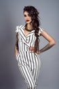 Portrait of young gorgeous dark-haired tattooed lady with braid wearing stylish striped overall with short sleeves and necklace