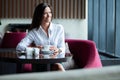 Portrait of young gorgeous female drinking tea and looking with smile out of the coffee shop window while enjoying her Royalty Free Stock Photo