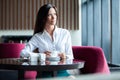 Portrait of young gorgeous female drinking tea and looking with smile out of the coffee shop window while enjoying her Royalty Free Stock Photo