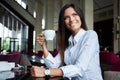 Portrait of young gorgeous female drinking tea and looking with smile out of the coffee shop window while enjoying her Royalty Free Stock Photo