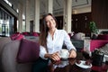 Portrait of young gorgeous female drinking tea and looking with smile out of the coffee shop window while enjoying her Royalty Free Stock Photo