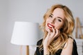 Portrait of young gorgeous woman with beautiful smile, red lips, day makeup, sensually touching her face in white room Royalty Free Stock Photo