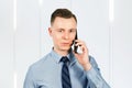 Portrait of young guy businessman dressed in blue shirt and tie, talking on the mobile phone Royalty Free Stock Photo