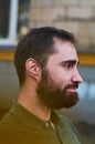 Portrait of young guy with dark beard with various emotions on his face in green shirt.