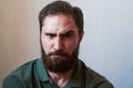 Portrait of young guy with dark beard with various emotions on his face in green shirt.