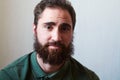 Portrait of young guy with dark beard with various emotions on his face in green shirt.