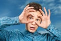 Portrait young guy dressed blue shirt man open his eyes wide with hands fingers and mouth. Man on blue sky background Royalty Free Stock Photo