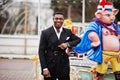 Portrait of young and handsome african american businessman in suit pose background carousel attractions with big pig