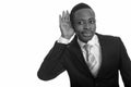 Portrait of young handsome African businessman in suit listening Royalty Free Stock Photo