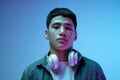 Portrait of young handsome asian man with headphones attentively looking at camera, posing against blue background in Royalty Free Stock Photo