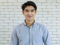 Portrait of young and handsome Asian man with smile and happy friendly face on white brick wall background Royalty Free Stock Photo