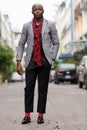 Full body shot of young bald African businessman with scarf outdoors Royalty Free Stock Photo