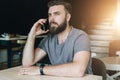 Portrait of young handsome bearded hipster man sitting in cafe at table and talking on his cell phone. Telephone Royalty Free Stock Photo