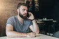 Portrait of young handsome bearded hipster man sitting in cafe at table and talking on his cell phone. Telephone Royalty Free Stock Photo