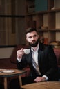 Portrait of a young handsome bearded man. A businessman in a suit sits at a table in a cafe or restaurant. Royalty Free Stock Photo