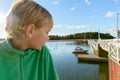 Profile view of young handsome boy looking at view of wooden pier near the river Royalty Free Stock Photo