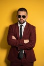 Portrait of young handsome business man in burgundy suit looking on you seriously wearing sunglasses with arms folded Royalty Free Stock Photo