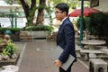 Portrait of young handsome businessman is holding a laptop on his hands in nature blurred background. Royalty Free Stock Photo