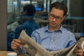 Portrait of a young handsome businessman reading a newspaper at his breakfast in coffee shop Royalty Free Stock Photo