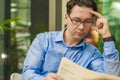 Portrait of a young handsome businessman reading a newspaper at his breakfast in coffee shop Royalty Free Stock Photo