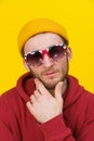 Portrait of a young handsome caucasian man in casual wear, sunglasses looking at camera on yellow background. Stylish Royalty Free Stock Photo