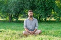 Portrait of young handsome European man in casual clothing sitting on a grass in summer park Royalty Free Stock Photo