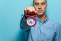 Portrait of a young handsome guy in blue shirt posing with red clock Royalty Free Stock Photo