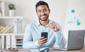 Portrait of a young handsome happy mixed race businessman using social media on his phone while working alone on a Royalty Free Stock Photo