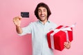 Portrait of young handsome happy overjoyed man male guy showing credit card hold red box gift wear glasses isolated on Royalty Free Stock Photo