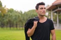 Young thoughtful Hispanic man carrying jacket over shoulder at the park Royalty Free Stock Photo