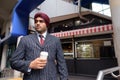 Young handsome Indian Sikh businessman holding disposable coffee cup Royalty Free Stock Photo