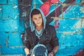 Portrait of a young handsome italian boy with skate and hood posing in the city urban graffiti background looking sidewards Royalty Free Stock Photo