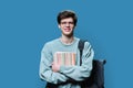 Portrait of young male college student in glasses with backpack on blue background Royalty Free Stock Photo