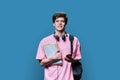 Portrait of young male college student with headphones backpack smartphone on blue background Royalty Free Stock Photo