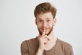 Portrait of young handsome man with beard looking at camera smiling showing to keep silence over white background. Royalty Free Stock Photo