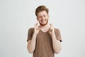 Portrait of young handsome man with beard praying hoping over white background.