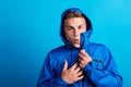 Portrait of a young man with blue anorak in a studio, feeling cold. Copy space.