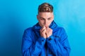 Portrait of a young man with blue anorak in a studio, feeling cold. Copy space.