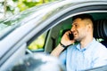 Portrait of young handsome man driving car and speaking on mobile phone Royalty Free Stock Photo