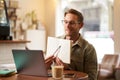 Portrait of young handsome man in glasses, private tutor teaching student online, pointing at his notebook, showing Royalty Free Stock Photo