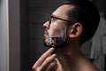 Portrait of a young handsome man with glasses shaves in the bathroom before work. profile of a serious successful businessman goin Royalty Free Stock Photo