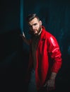 Portrait Of Young Handsome Man. Handsome man wearing red leather jacket on naked muscular torso on dark background Royalty Free Stock Photo