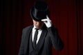 Portrait of young handsome man illusionist touching brim of top hat