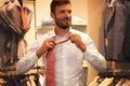 Handsome man trying tie in menswear
